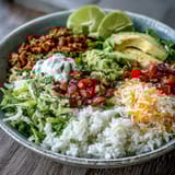 A close-up of a Turkey Taco Bowl with avocado, cheese, sour cream, and fresh cilantro.