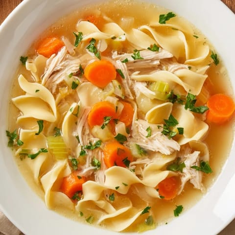 Hearty Chicken Noodle Soup: golden egg noodles swim in a flavorful broth, garnished with fresh parsley for serving.