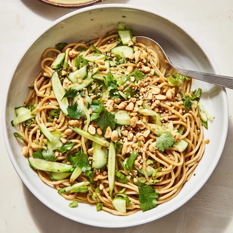 A vibrant Spicy Sesame Noodle Salad served in a bowl, topped with toasted sesame seeds and peanuts.