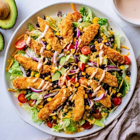 A vibrant plate of Crispy Chicken Taco Salad featuring black beans, avocado, cheddar cheese, and crunchy tortilla strips for a Tex-Mex lunch.