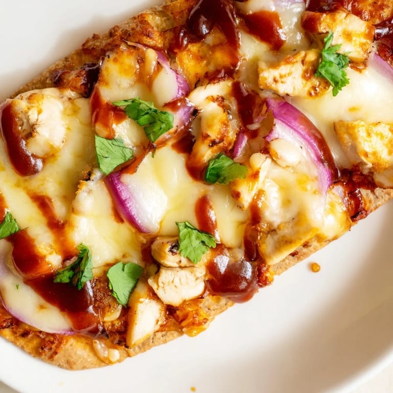 Sizzling BBQ Chicken Flatbread fresh from the oven, golden and bubbly with mozzarella, savory chicken, and vibrant red onions, perfect for a quick dinner.