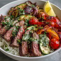 Golden-brown steak and roasted vegetables over fluffy rice in a Sheet Pan Steak and Veggie Bowl, finished with fresh herbs and lemon.