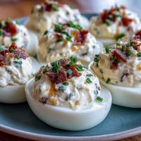 Spicy jalapeño popper deviled eggs with creamy cheese filling and crispy bacon, perfect for parties.